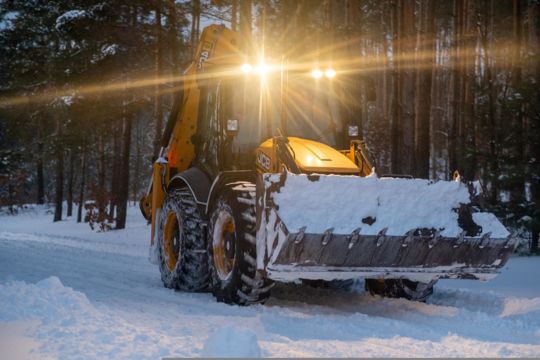Snow plow working in a forest.